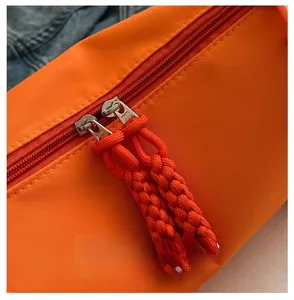 Detailed macro view of smooth silver metal double zippers on bright orange nylon bag