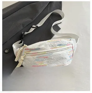 Vue détaillée du sac à bandoulière blanc avec broderies et détails de fermeture éclair