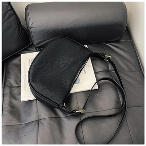Detailed macro view of black lychee grain leather crescent bag with adjustable strap