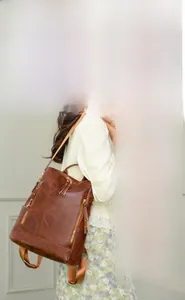 Brown vintage PU leather backpack showing detachable shoulder strap and side zipper detail