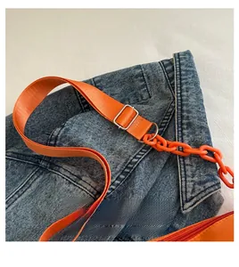 Detail of orange nylon bag featuring chunky chain decoration and wide shoulder strap