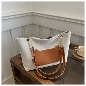 Detailansicht der beige gewebten Tragetasche mit brauner Ledertasche und Goldkette