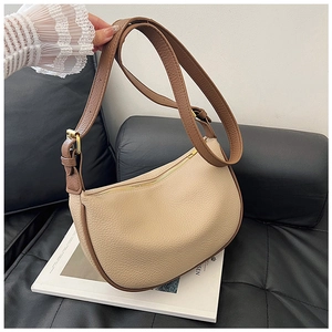Close-up of beige lychee grain leather with brown trim and golden zipper on half-moon bag