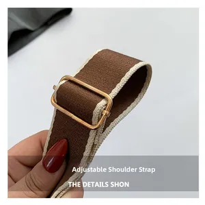Detail eines verstellbaren braunen Web-Schultergurts mit goldener Metallschnalle für Taschen