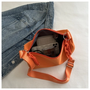 Interior view of orange nylon shoulder bag filled with phone, wallet and cosmetics