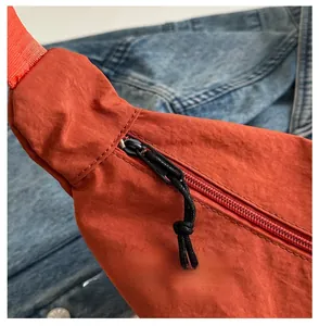 Detail eines schwarzen Reißverschlusses und Kordelzugs an der orangen Nylon-Tasche