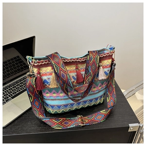 Detail of colorful woven straw bucket bag featuring fringe tassels and ethnic pattern strap