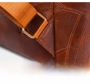 Detail of reinforced triangular stitching and gold metal buckle on dark brown leather bag