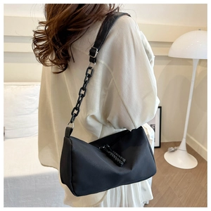 Detail of black nylon shoulder bag with stylish chunky chain and knotted zipper pulls