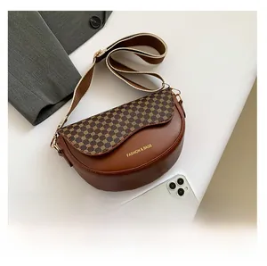 Makro-Detail der braunen Satteltasche mit Vintage-Muster und breitem Gurt