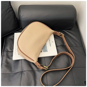 Macro detail of beige pebble leather crescent bag with gold zipper and stitching