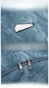 Detail display of blue denim backpack with silver metal ornament and dual metal zippers