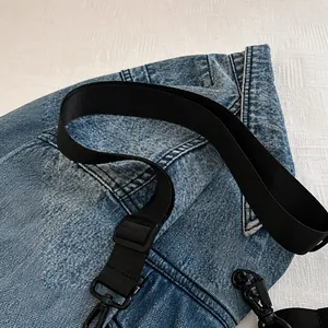 Détail de la large bandoulière en nylon et du tissu en denim délavé du sac de sport