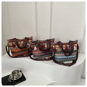 Three bohemian straw bucket bags with geometric patterns and colorful tassels on a white stand