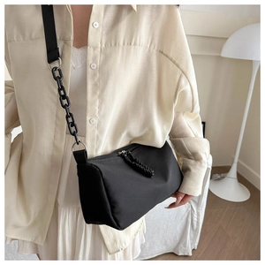Detail view of black nylon shoulder bag with thick chain strap and woven zipper pullers