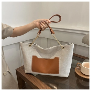 Detail der Canvas-Einkaufstasche mit brauner Ledertasche und Metallketten-Riemendesign