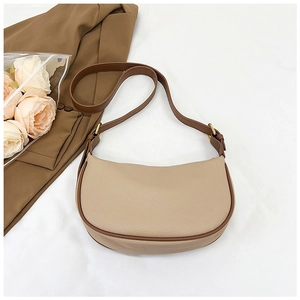 Detail of minimalist cream leather half-moon bag with brown strap and golden metal buckle