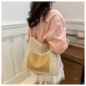 Close-up of woven straw tote bag with leather pocket and long shoulder straps