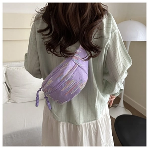 Détail du sac bandoulière violet avec broderies colorées et texture logo sur le matériau