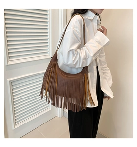 Sac hobo en similicuir marron avec de longues franges bohèmes porté par un mannequin