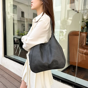 Side view of matte black oversized tote bag with minimalist seams and logo detail