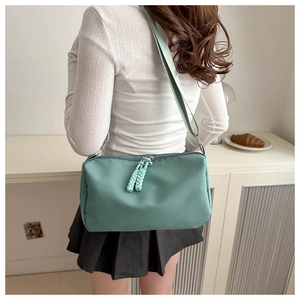 Detail view of mint green nylon crossbody bag with distinctive woven rope zipper pulls