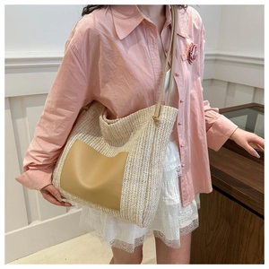 Detailed view of woven straw tote bag texture with tan leather patch and shoulder strap