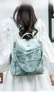 Rear view of a model wearing the blue soft leather backpack with stylish diagonal zipper detail