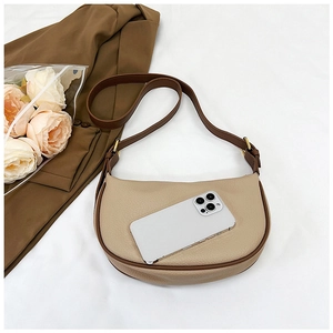 Beige crescent bag detail showing interior capacity next to a smartphone