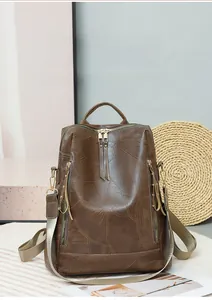 Detail of dark brown vintage PU leather backpack with leaf vein texture and gold zippers