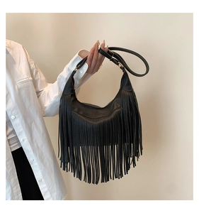 Détail du sac croissant en cuir grainé noir avec de longues franges et des boucles dorées