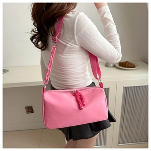 Pink cylindrical nylon shoulder bag featuring dual zippers and stylish acrylic chain detail