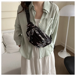 Détail du sac bandoulière en croissant avec broderie colorée sur tissu noir texturé