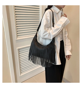 Détail d'un sac porté épaule rétro en denim noir avec des franges et boucles dorées