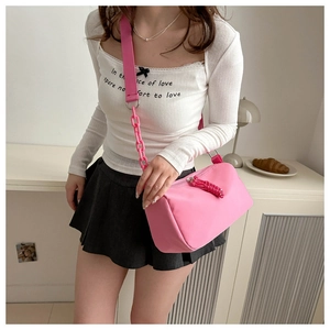 Pink nylon crossbody bag detail showing wide strap and decorative plastic chain