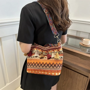 Bohemian woven bucket bag with tassels and colorful geometric strap shown on a model