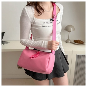 Detail of rose pink nylon crossbody bag showing dual zippers and adjustable shoulder strap