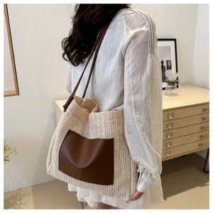 Detail of cream woven tote bag with brown leather pocket and slim shoulder straps