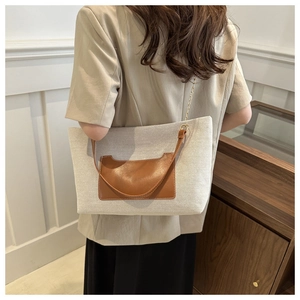 Große beige Nylon-Tote mit braunen Lederakzenten und Kettenriemen am Rücken getragen
