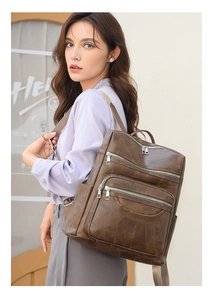 Detail view of a vintage dark brown PU leather backpack with multi-zipper pockets for travel
