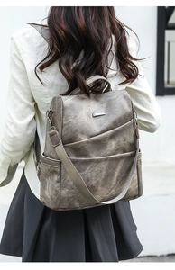 Macro detail of a vintage grey soft leather backpack featuring layered zipper compartments