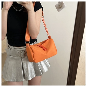 Detail of orange nylon crossbody bag with bold plastic chain and woven zipper pull
