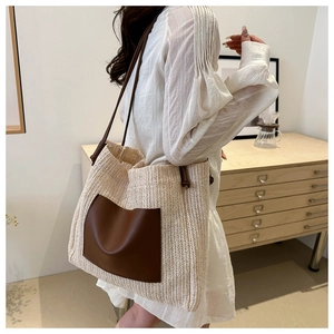 Detail of a large woven tote bag with a brown leather pocket on a white summer dress