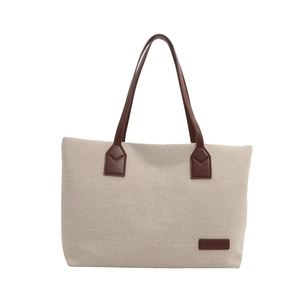 Minimalist beige canvas tote bag with brown leather handles and brand tag on white background