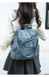 Detailed back view of a woman wearing the retro blue PU leather backpack with nylon straps