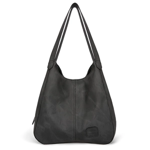 Detail view of the black matte leather tote bag featuring vertical seams and logo patch
