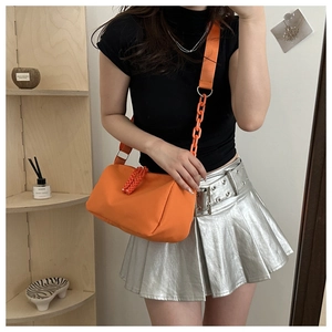 Detail view of bright orange nylon crossbody bag with chunky chain and thick woven strap