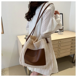 Detailed side view of the large woven straw tote bag with brown leather front pocket