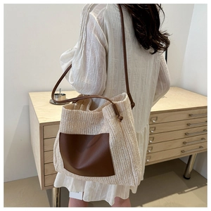Detail of hand-woven straw tote with premium brown leather straps and front pocket