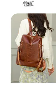 Detail of dark brown patchwork leather backpack with rivets and wide fabric strap